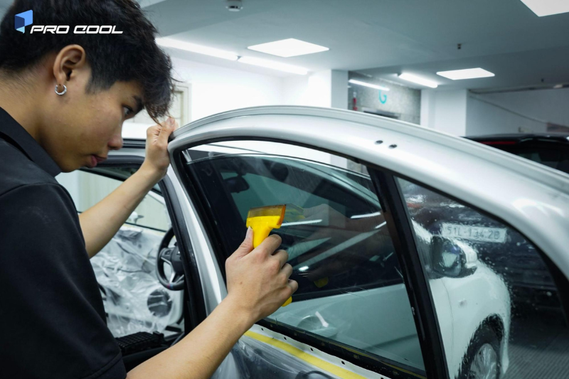 Kỹ thuật viên thi công dán phim cách nhiệt cho kính sườn sau xe hơi 