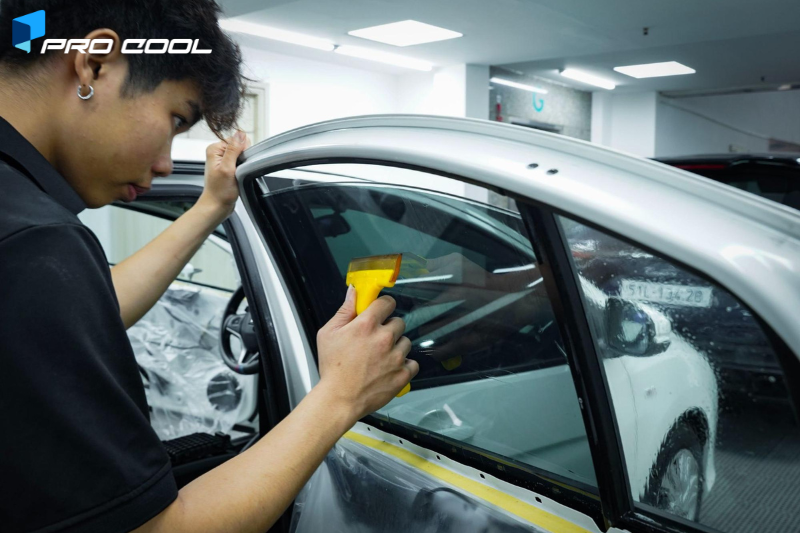 Kỹ thuật viên thi công dán phim cách nhiệt Pro Cool cho kính tài phụ
