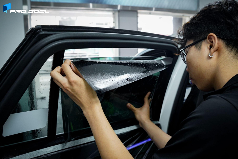 Kỹ thuật viên đang thực hiện dán phim cách nhiệt Pro Cool cho kính sườn sau